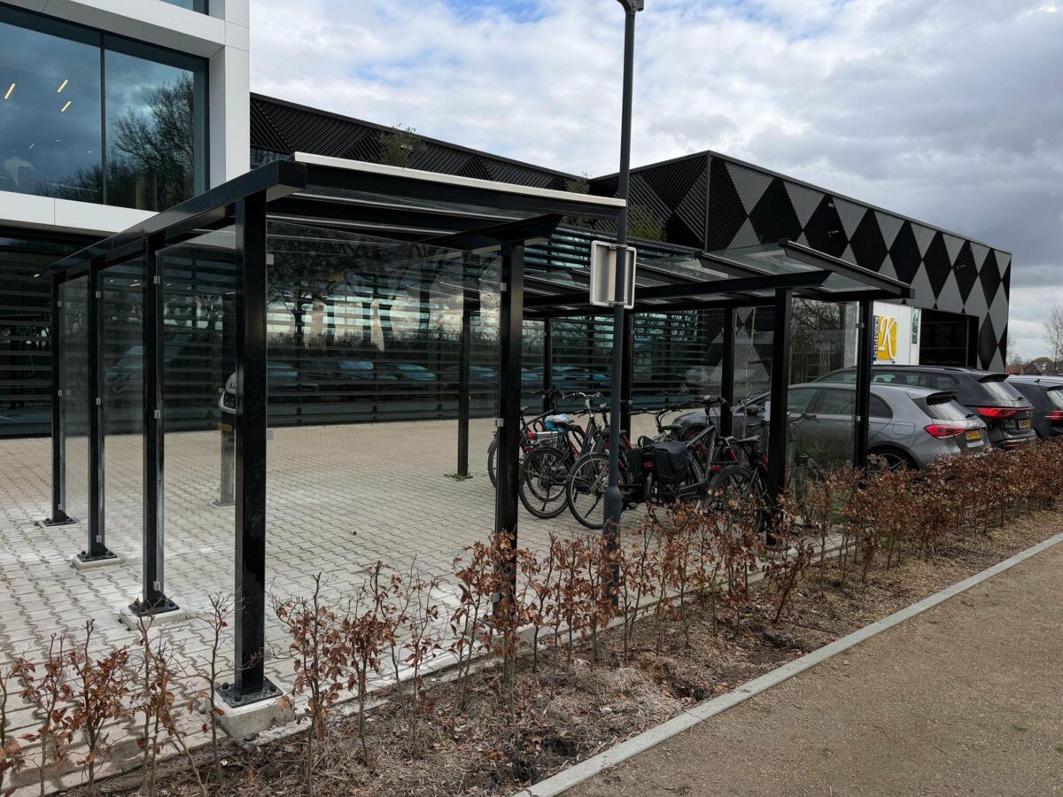 Veiligheid en design bij moderne fietsoverkappingen en rookoverkappingen 4 Twee fietsoverkappingen model City met glazen wanden en dak van veiligheidsglas geplaatst bij Kempen Cladding in Bergeijk